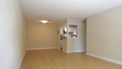 A room with a wooden floor and a small kitchenette in the corner.