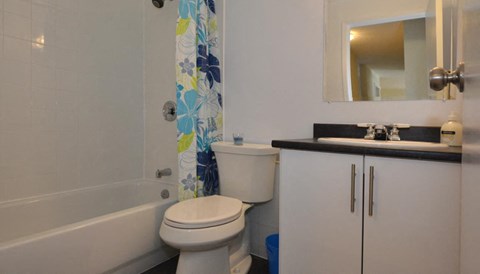 A white toilet sits in a bathroom next to a bathtub and a sink.