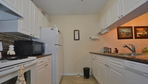 A kitchen with white cabinets and a black microwave.