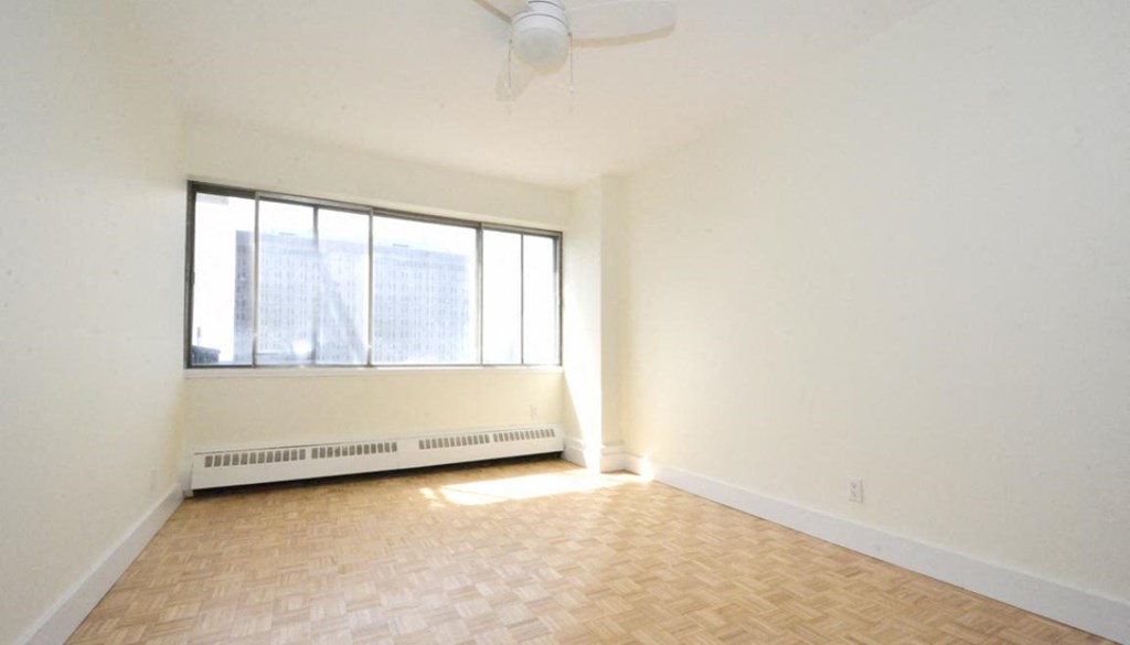 an empty living room with a large window and wooden floors