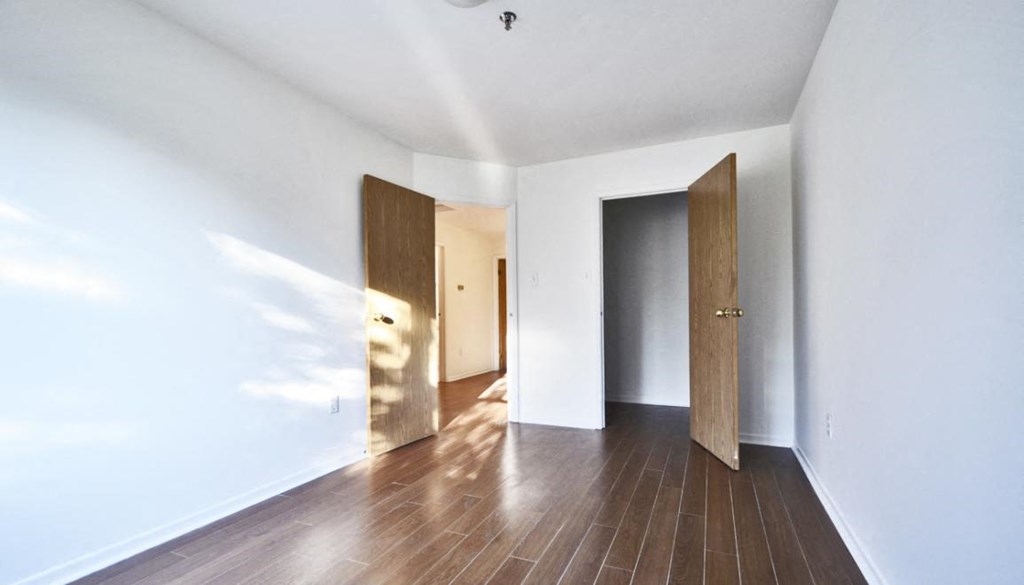 a hallway with white walls and wooden floors and two wooden doors