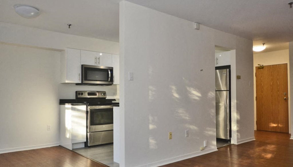 an empty kitchen with stainless steel appliances and a refrigerator