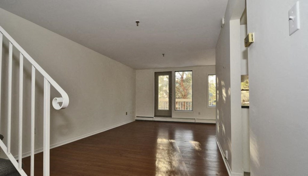 an empty living room with wood floors and a staircase