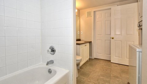 A white bathroom with a white tub and a white door.