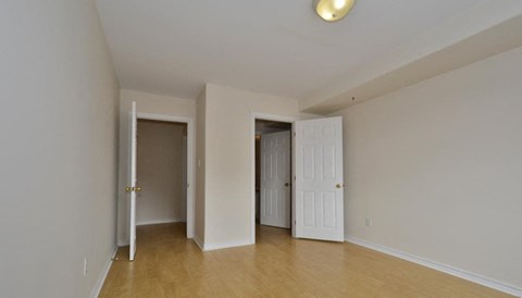 A room with white walls and wooden flooring, with two doors open.