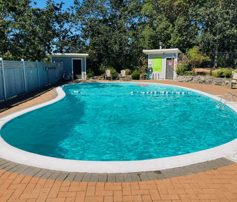 A small pool with a white border and a white building in the background.
