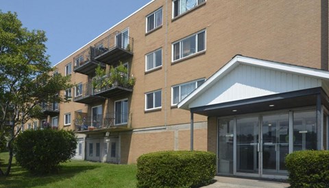 A building with a balcony and a small garden in front.