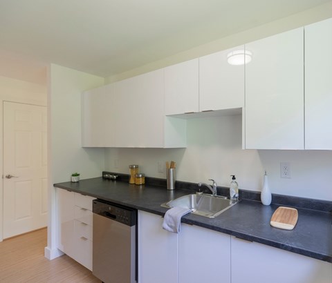 A kitchen with white cabinets and black countertops.