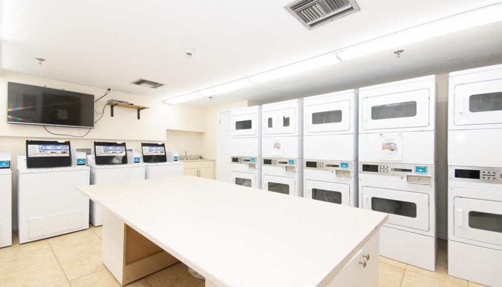 a laundry room with a white counter top and lots of white appliances