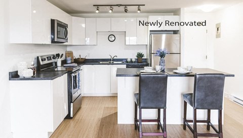 A newly renovated kitchen with a black countertop and white cabinets.