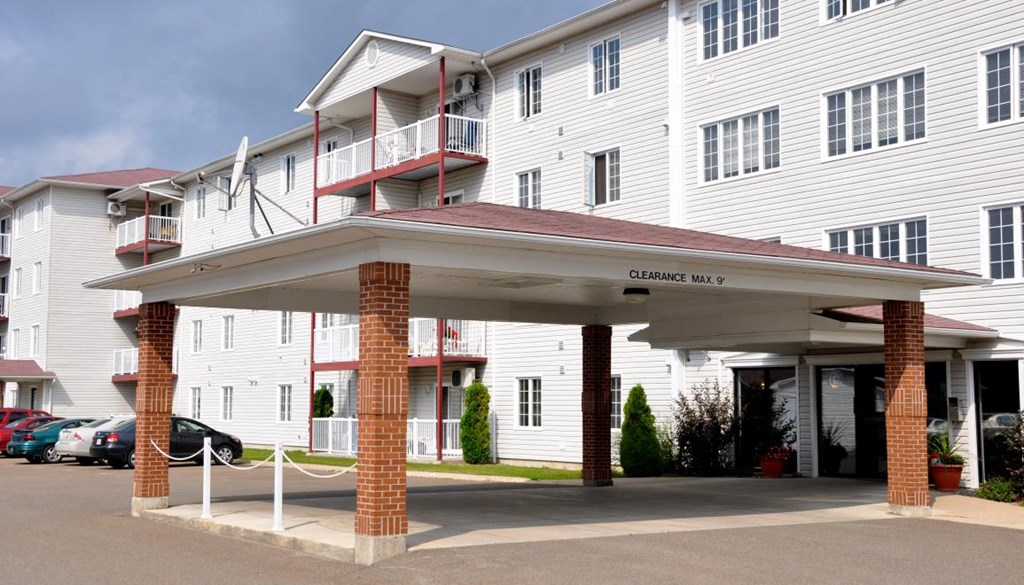 A white building with a red roof and a sign that says "CLEARANCE MAX 10".