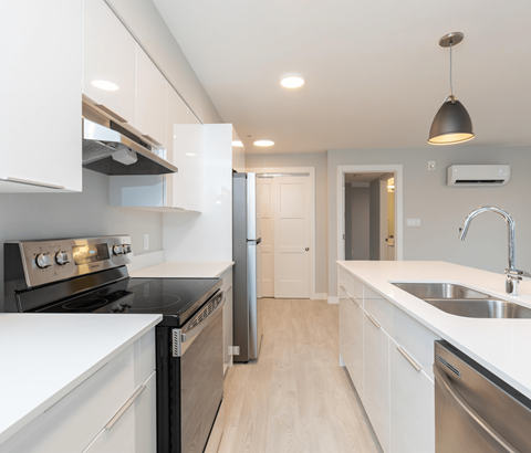 A modern kitchen with white cabinets and stainless steel appliances.