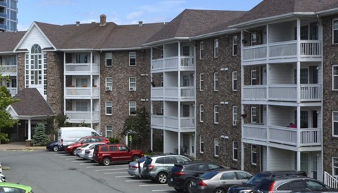 A parking lot with cars and apartment buildings in the background.