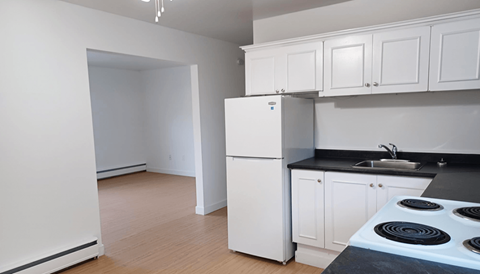 a kitchen with white cabinets and a white refrigerator and stove
