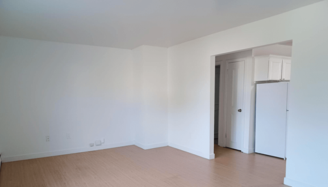 an empty living room with white walls and wood floors
