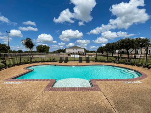 A large outdoor swimming pool surrounded by a black fence.