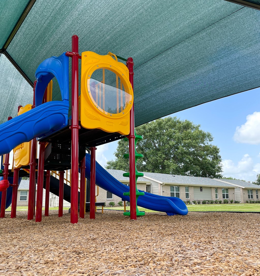 a playground with a blue and yellow play set under a canopy