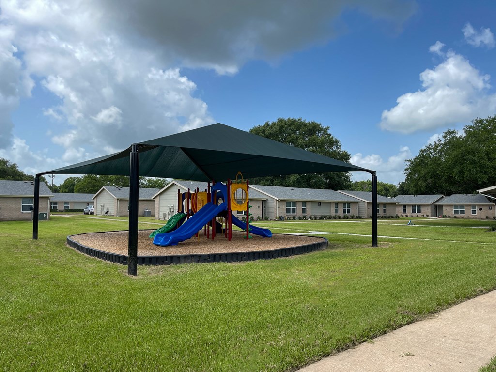 a playground with a canopy and slides in a park
