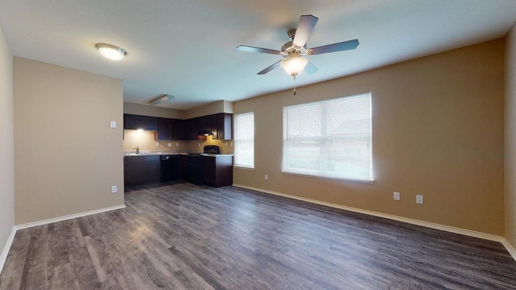 an empty living room with a ceiling fan and a window