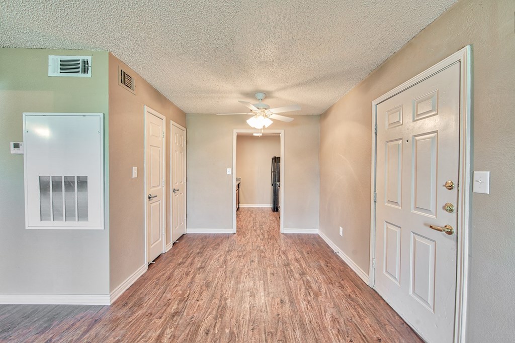 an empty hallway with a ceiling fan and white doors