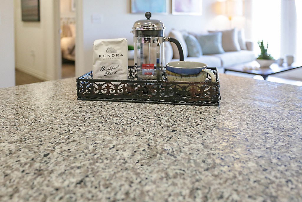 a coffee pot and a cup on a table with a couch in the background