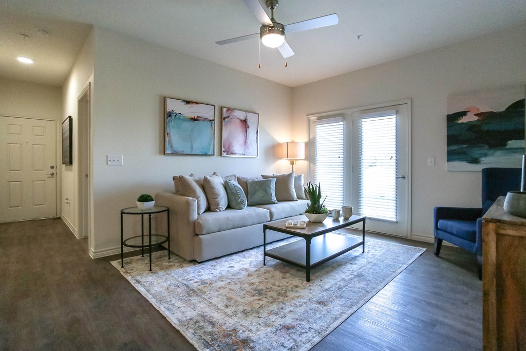 a living room with white walls and a ceiling fan