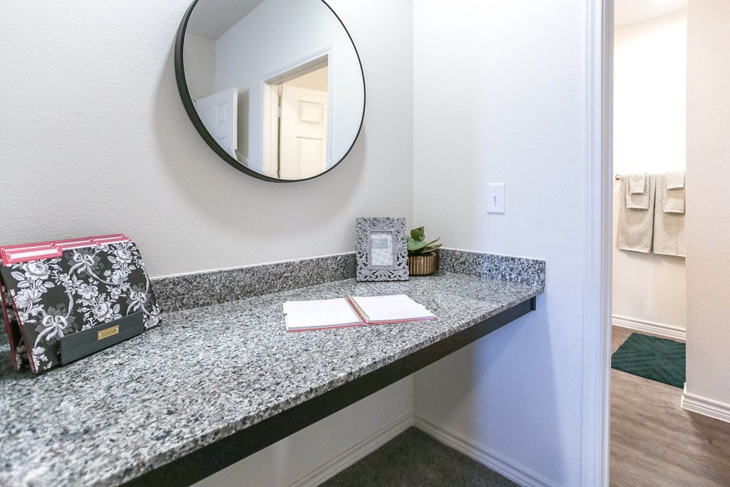 a bathroom with a granite countertop and a round mirror