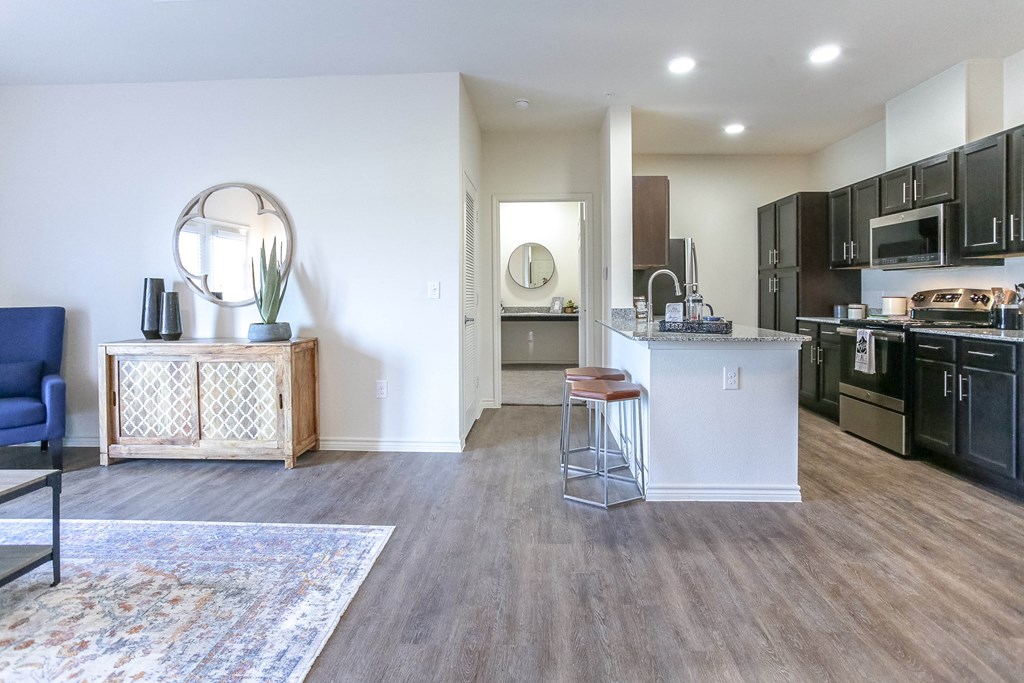 a spacious living room with a kitchen in the background