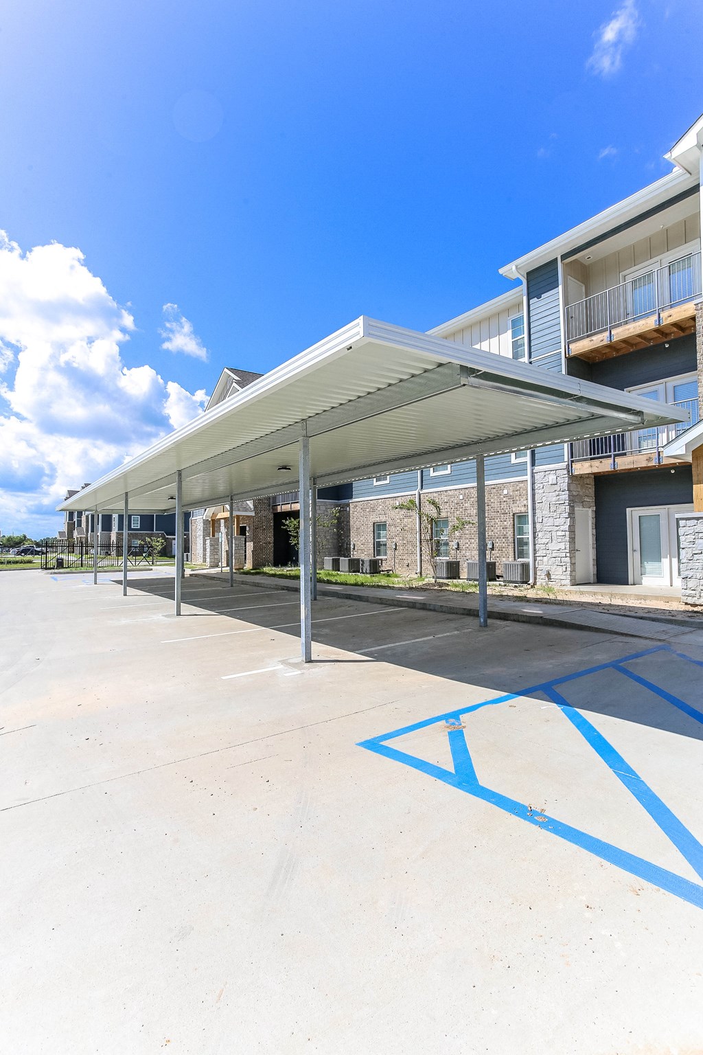 a covered parking lot with an apartment building in the background