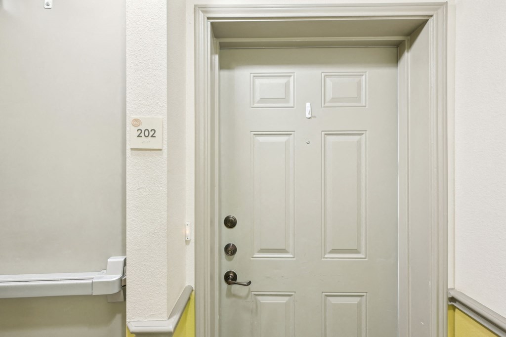 A white door with a number 202 on the wall above it.
