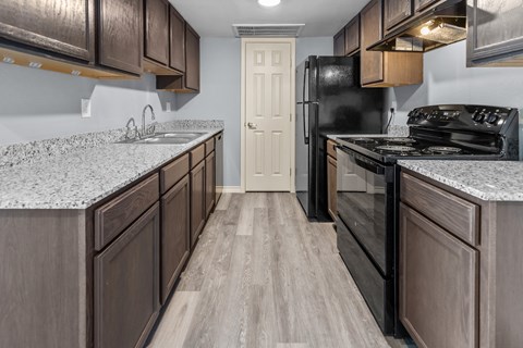a kitchen with wooden cabinets and granite counter tops and a black refrigerator