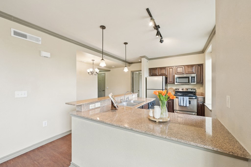 A kitchen with a granite countertop and a vase of flowers on it.