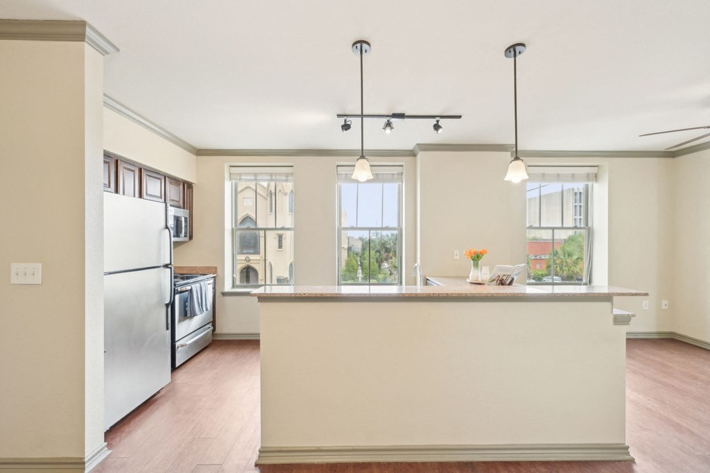 A kitchen with a refrigerator, a counter, and a window.