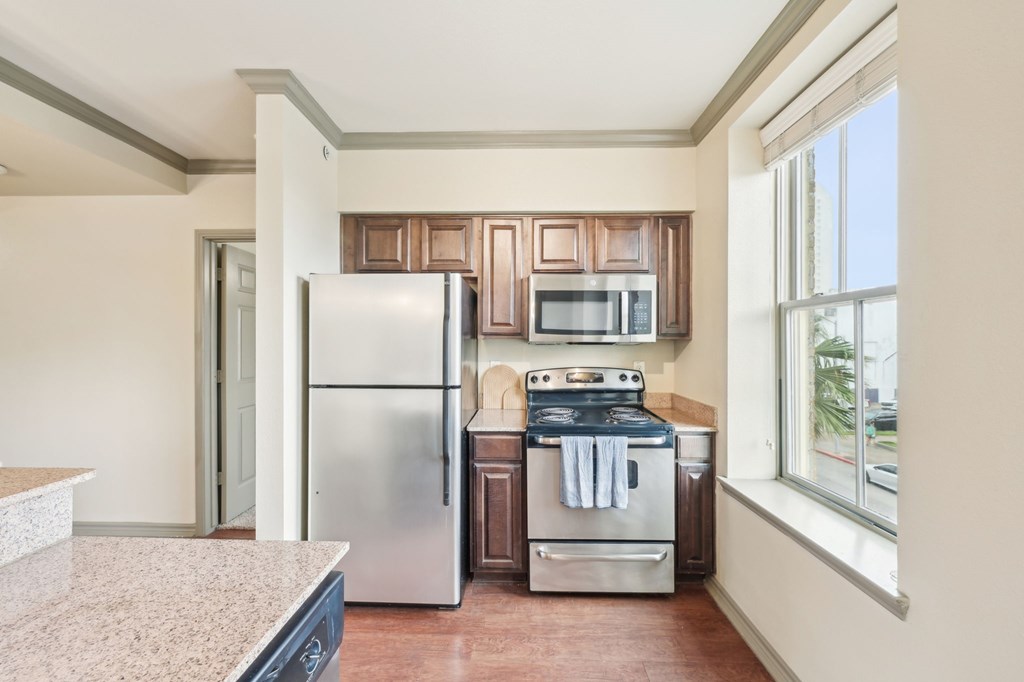 A kitchen with a refrigerator, oven, and microwave.