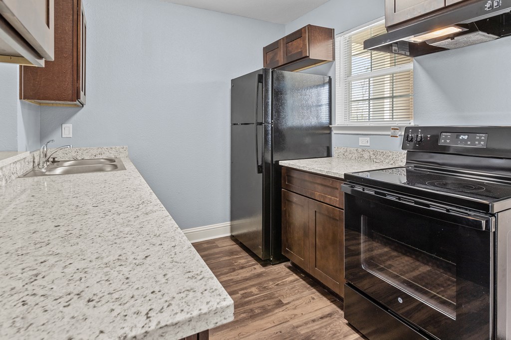 a kitchen with granite counter tops and a black refrigerator