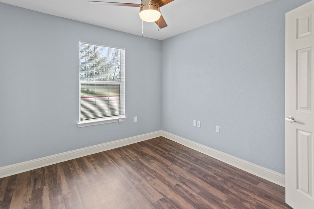 an empty room with wood floors and a window