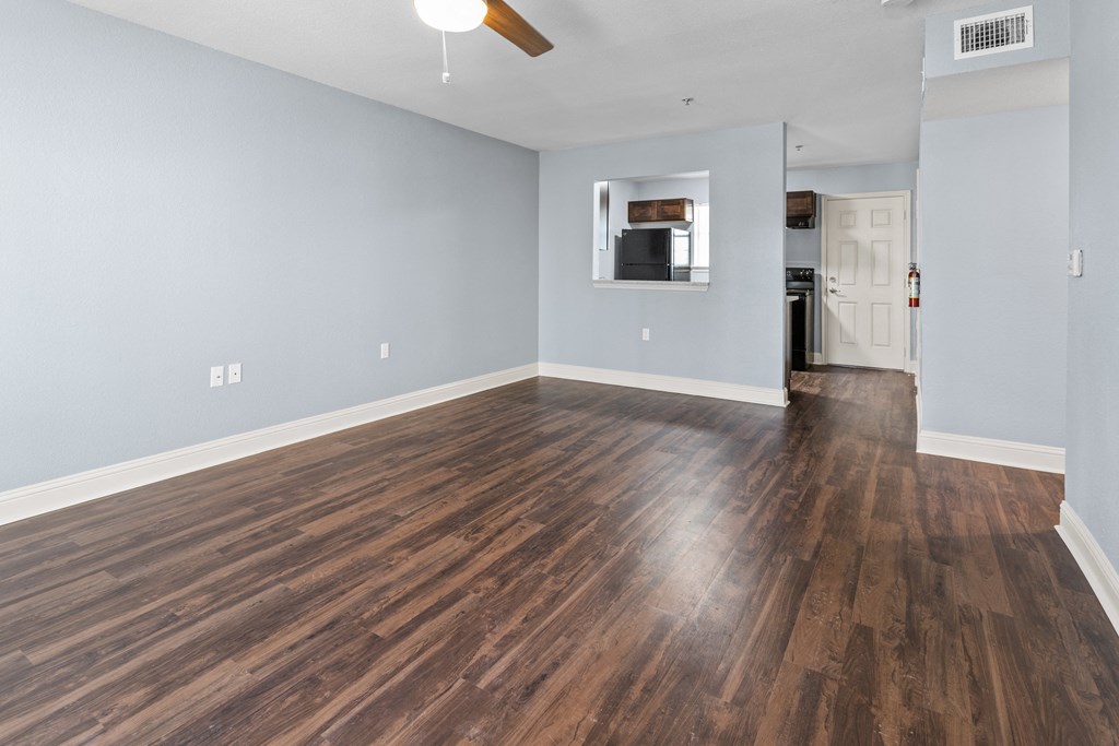 an empty living room with wood flooring and a ceiling fan
