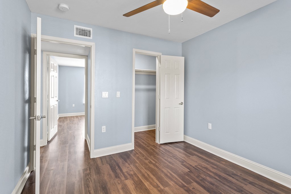 an empty room with blue walls and a ceiling fan