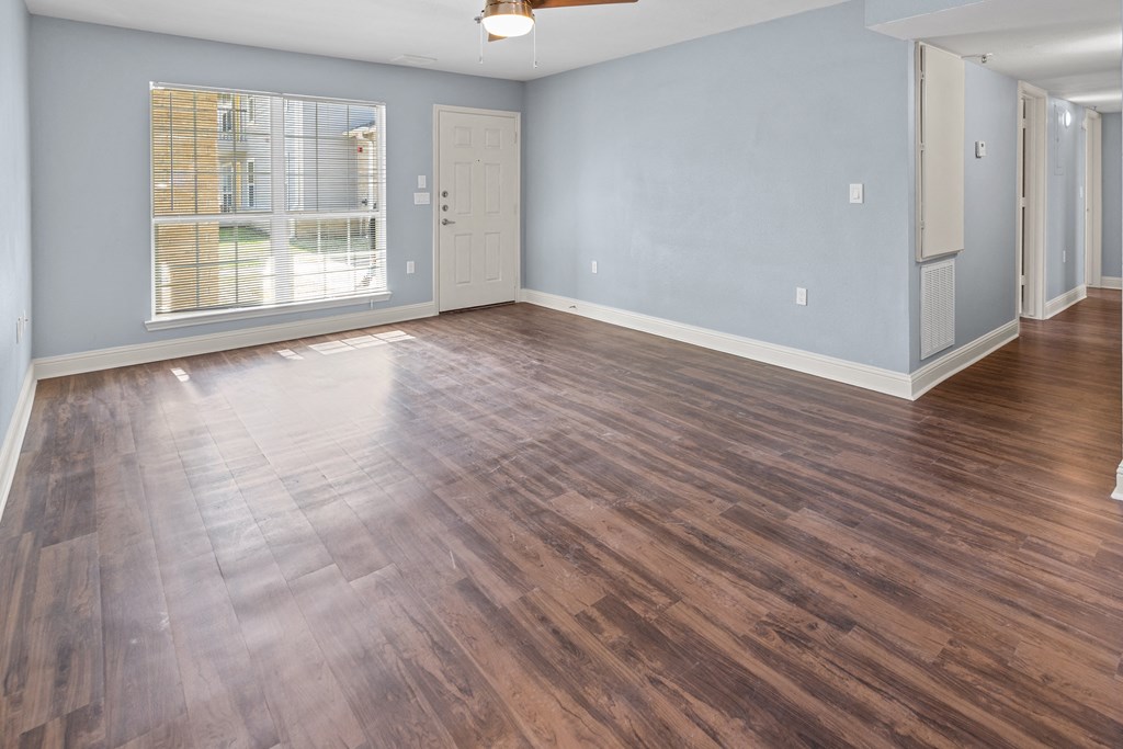 the living room and dining room of an empty house with wood flooring
