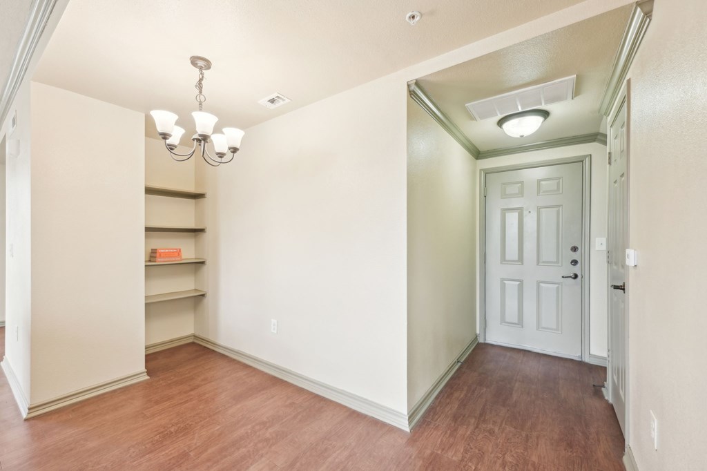 A hallway with a white door and a chandelier.