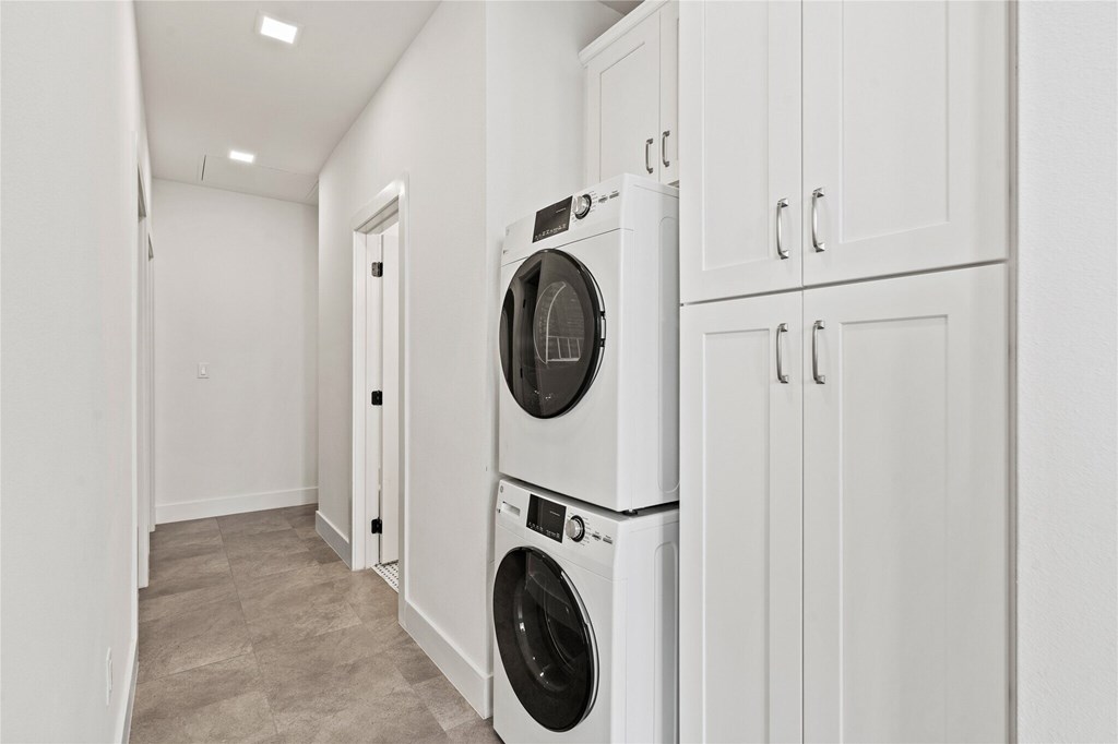 A white washer and dryer are stacked on top of each other in a laundry room.