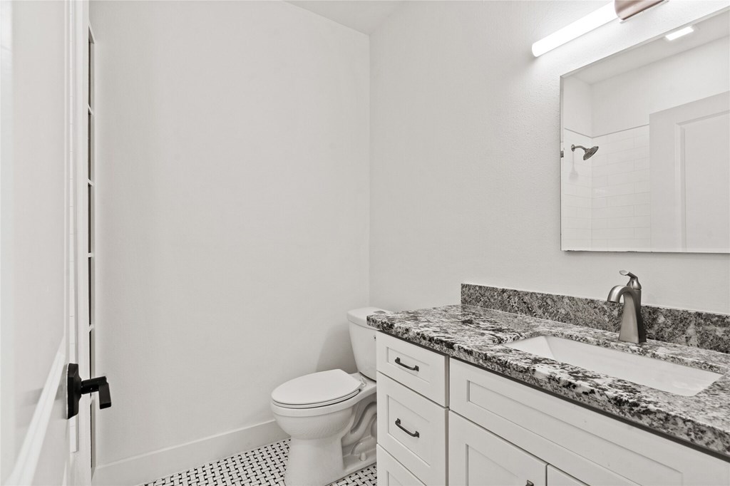 A white bathroom with a toilet, sink, and mirror.
