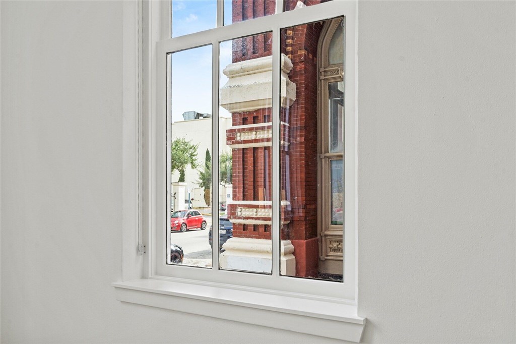 A window with a view of a street with cars and buildings.