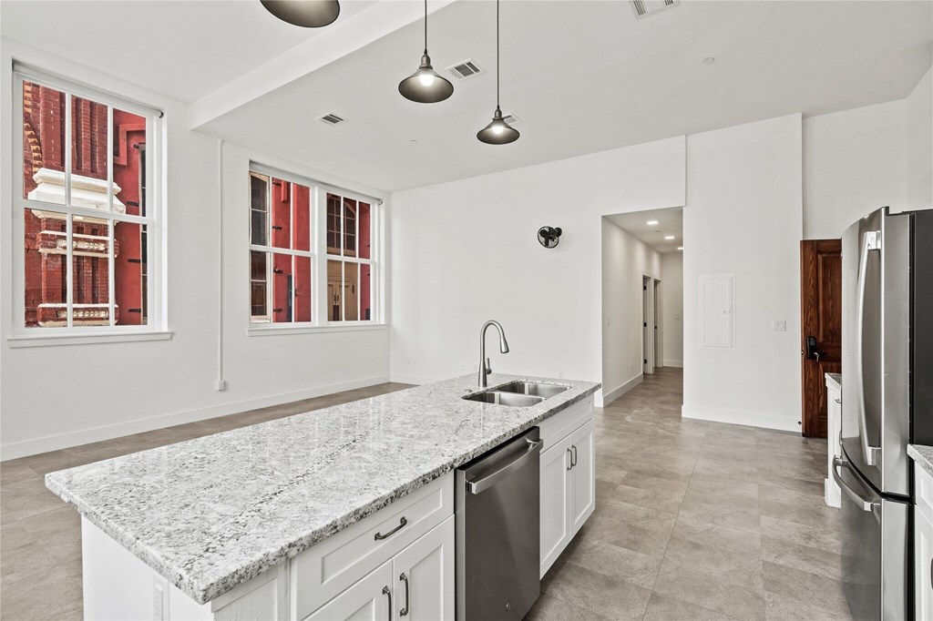 A kitchen with a granite countertop and stainless steel appliances.