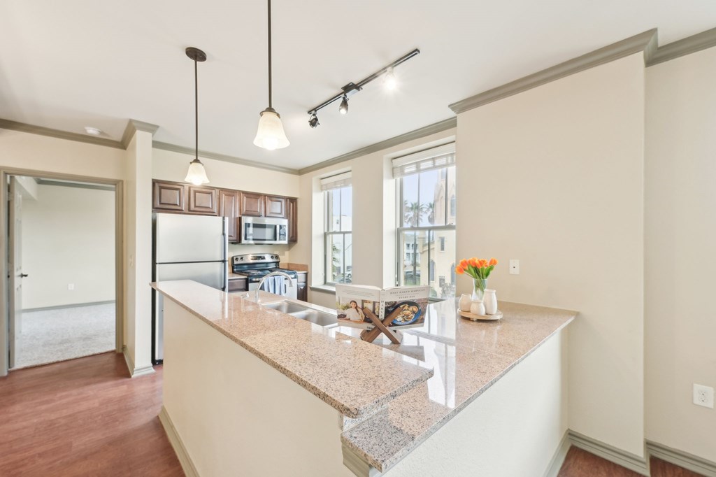 A kitchen with a granite countertop and pendant lights.