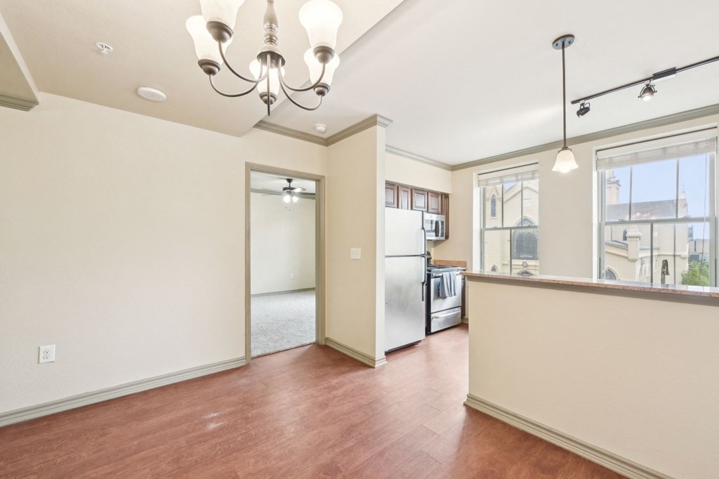 A kitchen with a refrigerator, wooden floors, and a chandelier.