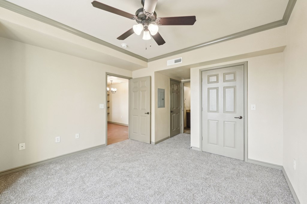 A room with a ceiling fan and carpeted floor.