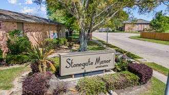 a sign that says stonegate manor apartments in front of a brick building