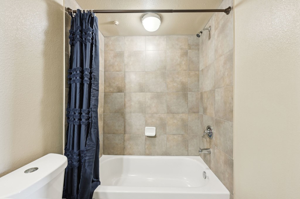 A bathroom with a white tub and a black shower curtain.
