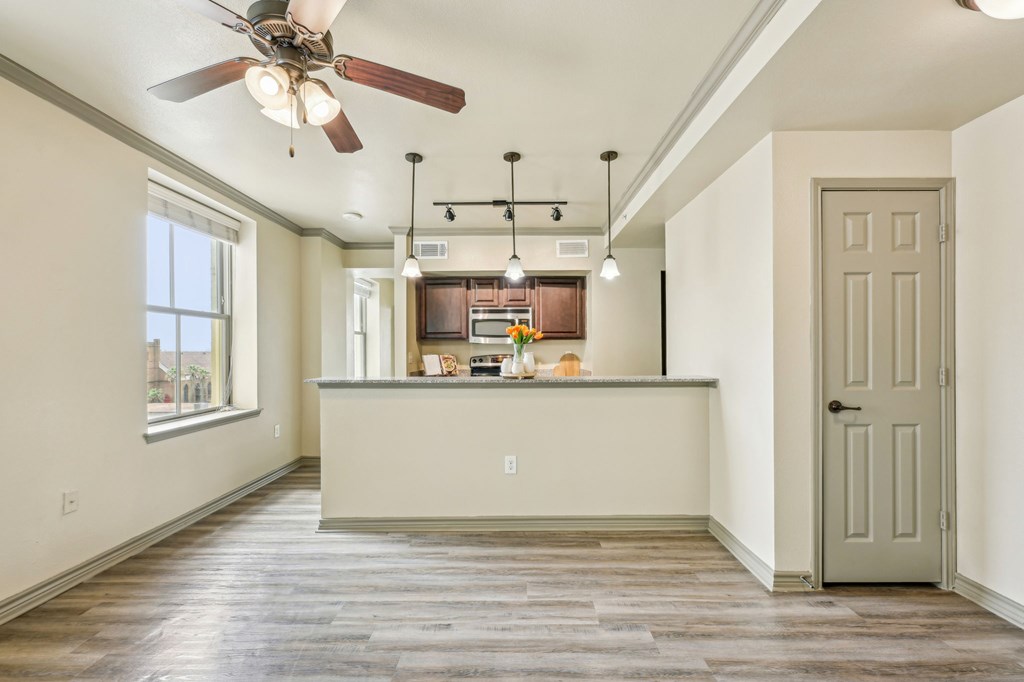 A kitchen with a fan and a bar counter.